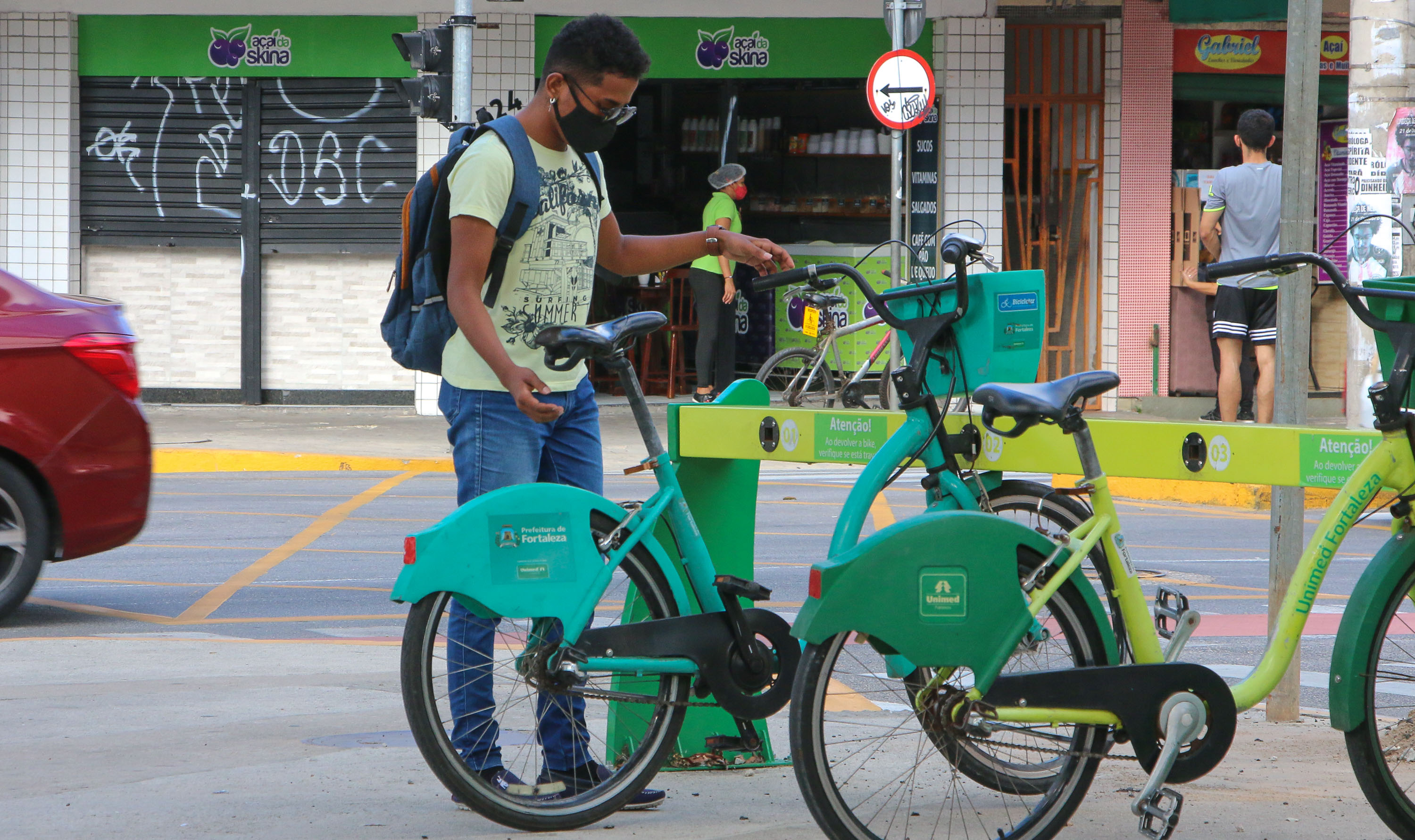 rapaz pega uma bicicleta numa estação do bicicletar